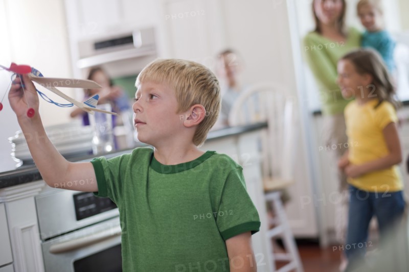 Young boy playing with toy airplane in kitchen. Photo. Tim Pannell