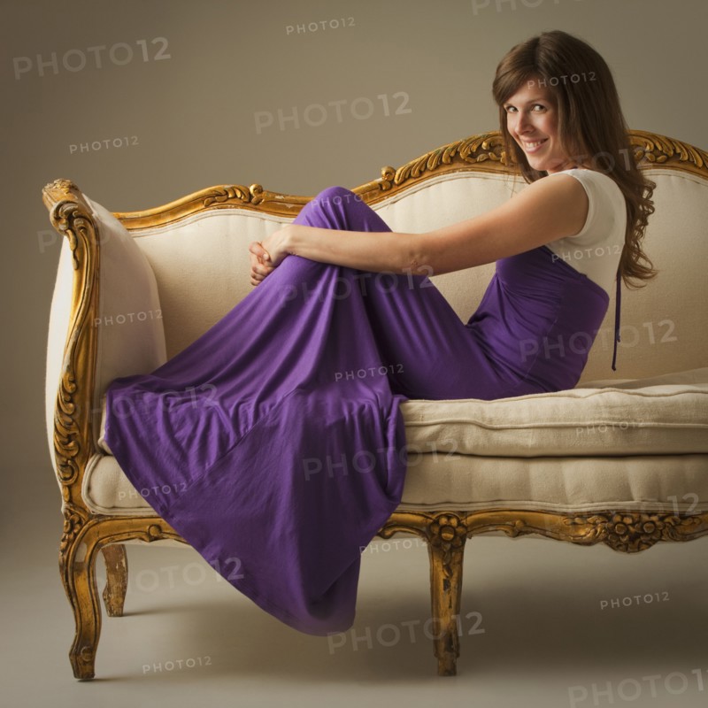 Elegant woman sitting on antique sofa. Photo. Mike Kemp