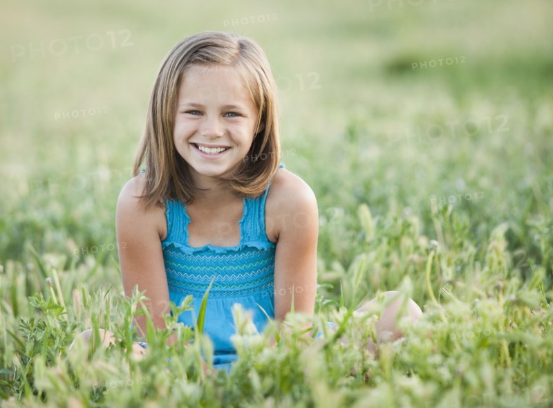 Young girl sitting in field. Photo. Mike Kemp