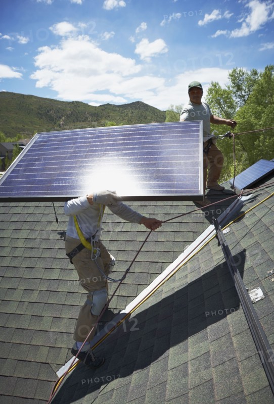 Construction workers installing solar panels on roof. Photo. Shawn O'Connor
