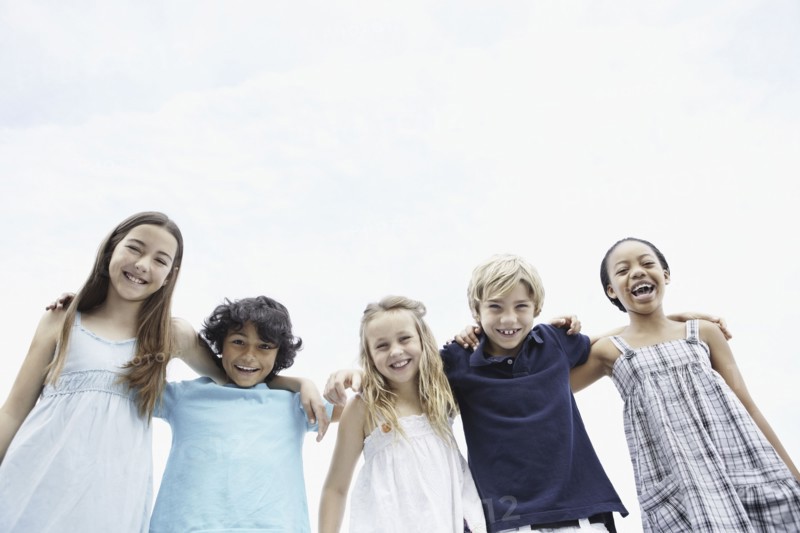 Young children with their arms around one another. Photo. momentimages