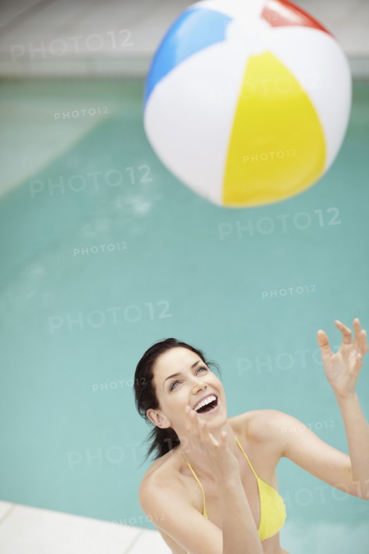 Attractive brunette playing with a beach ball. Photo : momentimages