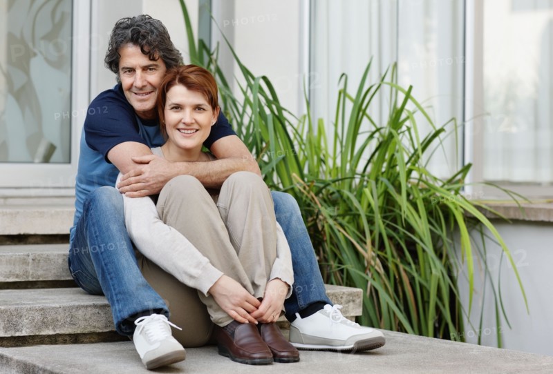Happy couple sitting on steps together. Photo. momentimages