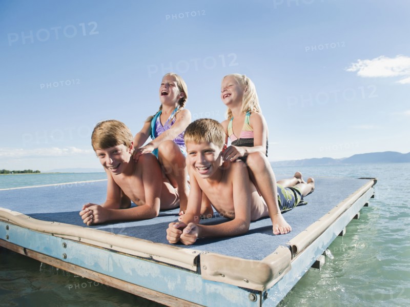 Kids (6-7,8-9,10-11,12-13) playing on raft on lake.