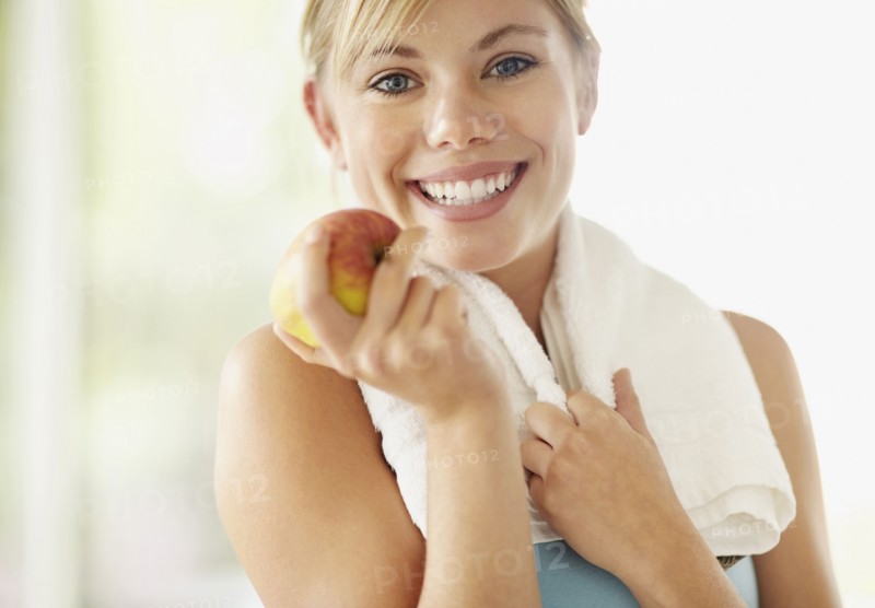 Portrait of young blonde woman holding apple. Photo : Momentimages