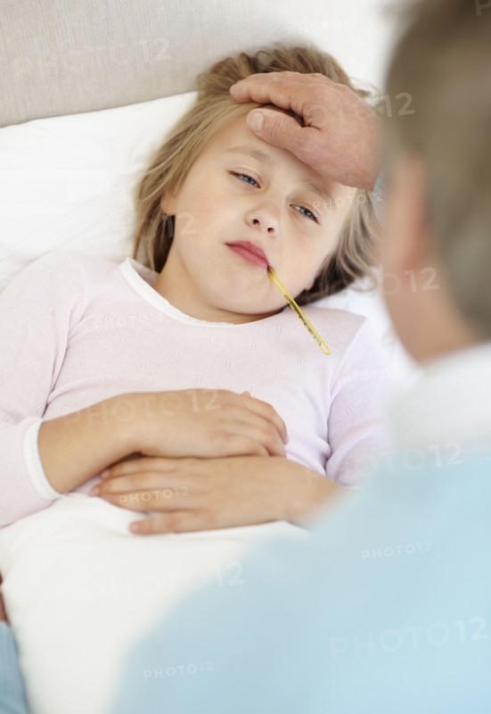 Grandfather tending granddaughter (10-11) lying in bed with thermometer in mouth. Photo : Momentimages