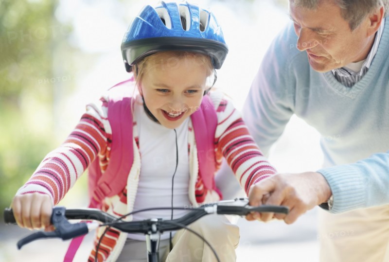 Grandfather helping granddaughter (10-11) riding bike. Photo : Momentimages