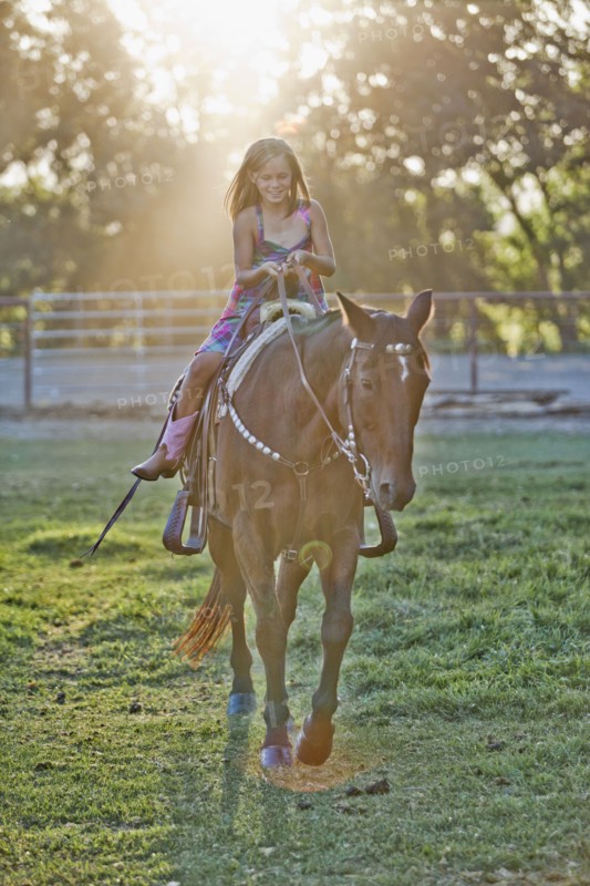 Girl (8-9) riding horse in paddock. Photo : Mike Kemp