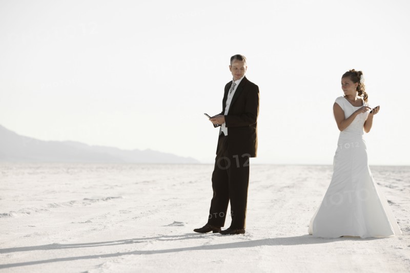 Bride and groom texting in desert. Photo : FBP