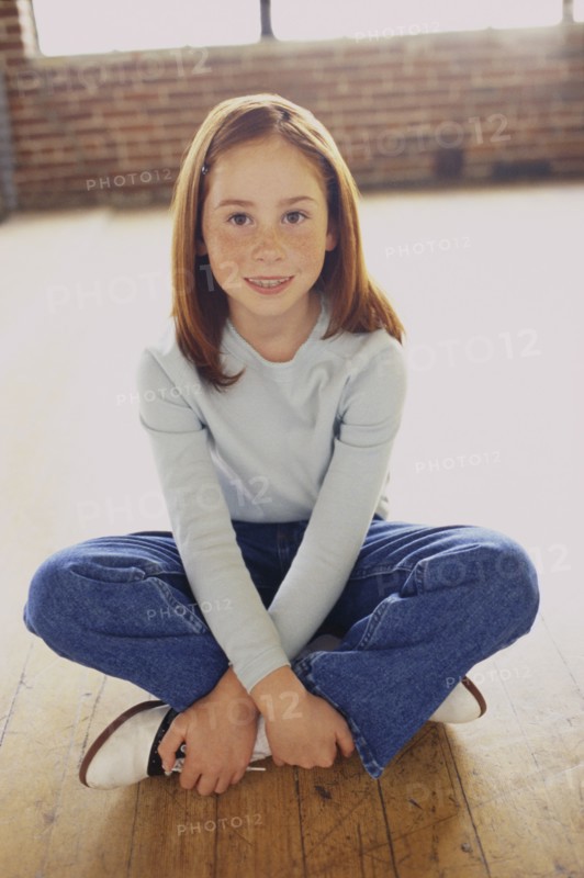 Cute young girl sitting cross legged. Photo : Fisher Litwin