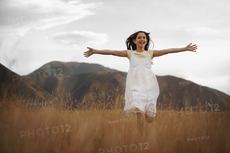 Girl (10-11) running through wheat field. Photo : FBP