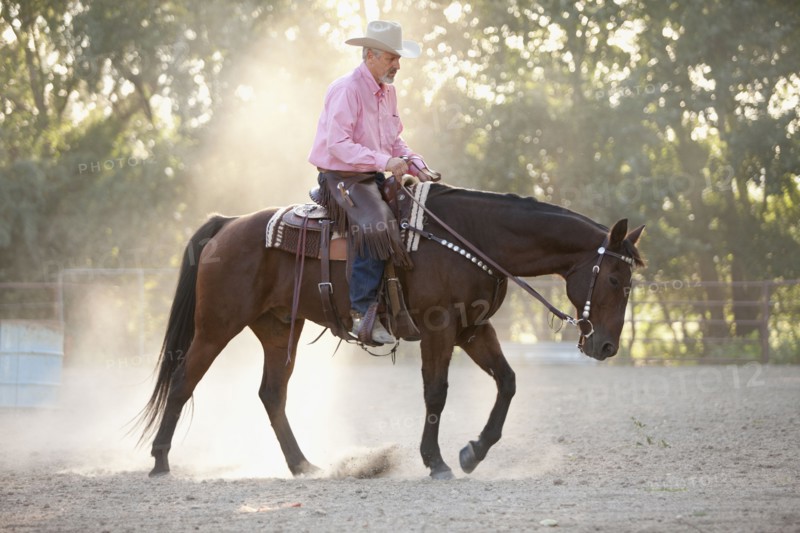 Senior man horseback riding in ranch. Photo : Mike Kemp