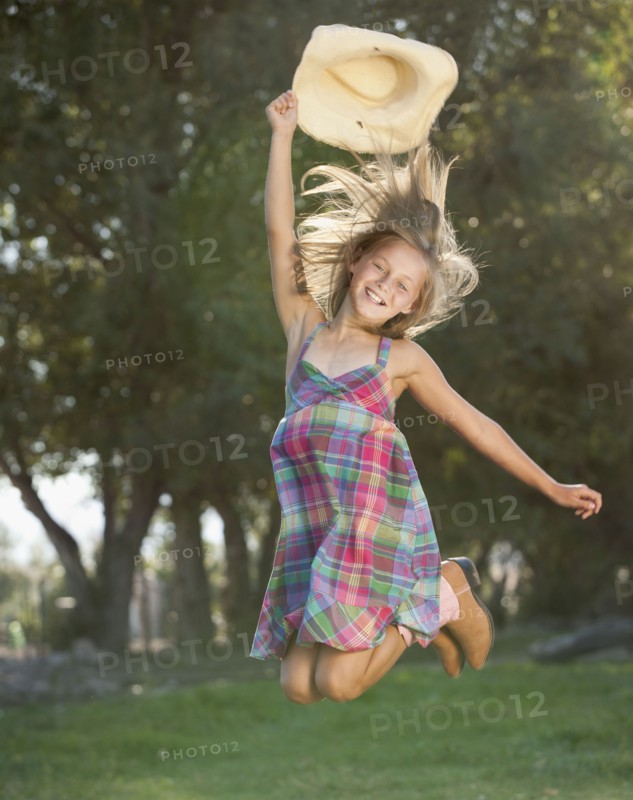 Portrait of smiling cowgirl (8-9) jumping. Photo : Mike Kemp