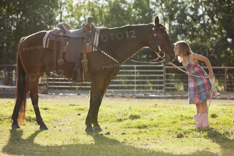 Cowgirl (8-9) kissing horse in ranch. Photo : Mike Kemp