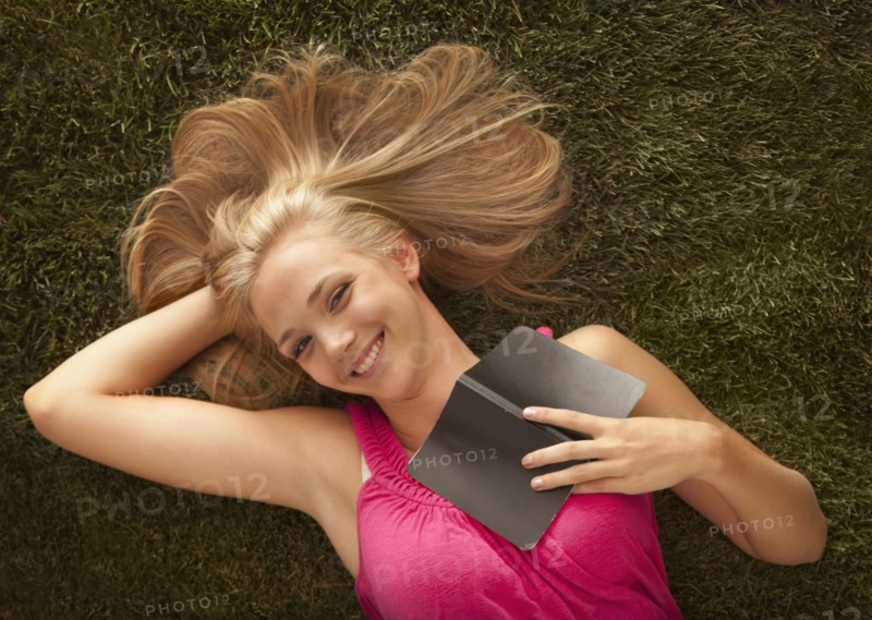 Young girl (16-17) lying on grass. Photo : Mike Kemp