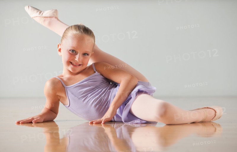 Portrait of female ballet dancer (6-7) stretching in dance studio. Photo : Mike Kemp