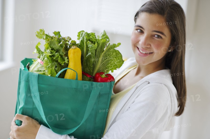 Portrait of girl (12-13) holding groceries .