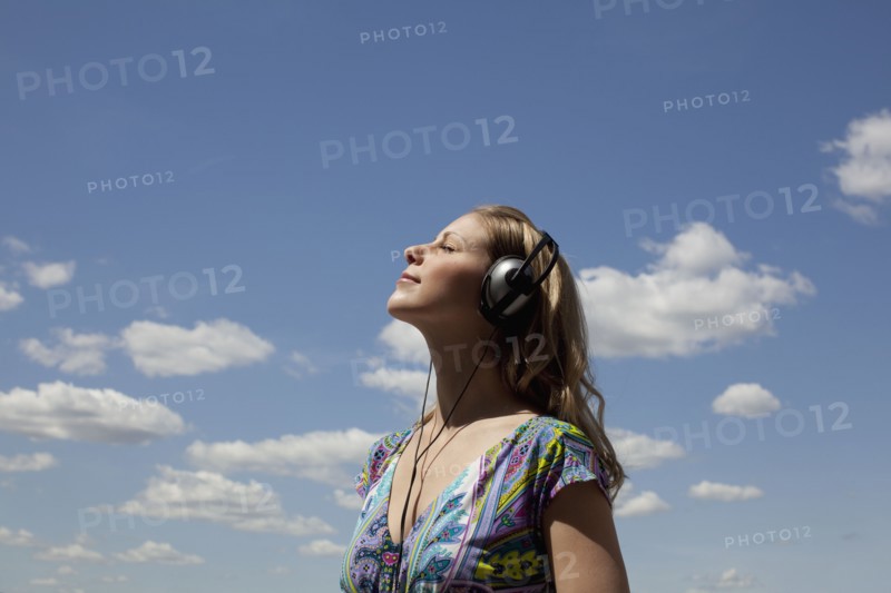Young woman listening to music outdoors. Photo : Johannes Kroemer
