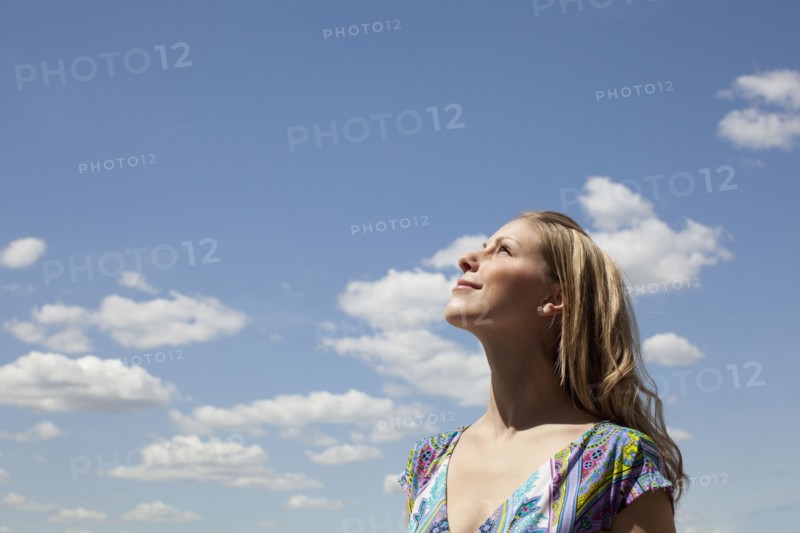 Young woman smiling against cloudy sky. Photo : Johannes Kroemer