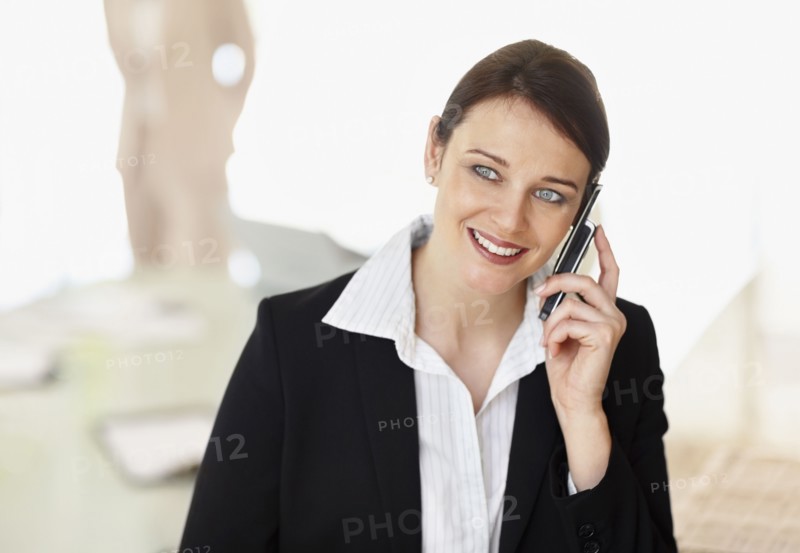 Smiling businesswoman using mobile phone. Photo : Momentimages