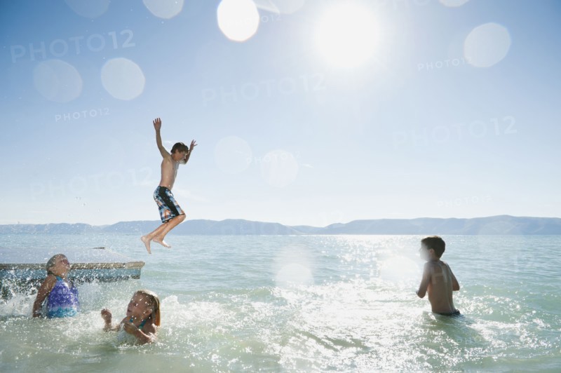 Kids (6-7,8-9,10-11,12-13) playing on raft on lake.