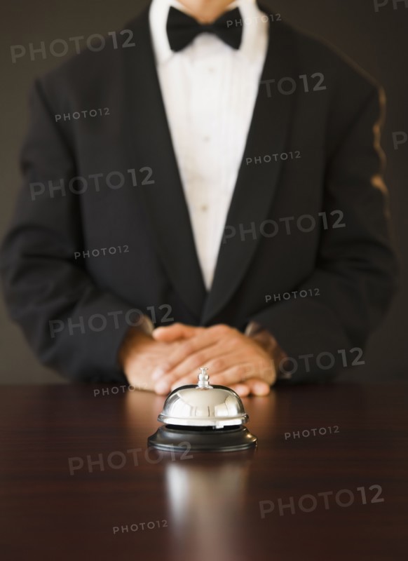 Service bell in the foreground, man wearing bow tie in the background, studio shot. Photo : Jamie Grill