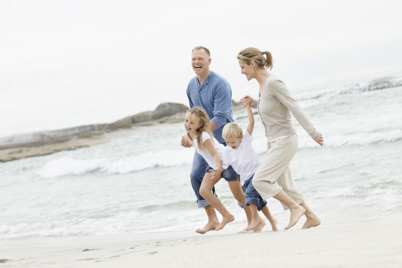 Girl (10-11) and boy (4-5) playing on beach with parents. Photo : Momentimages