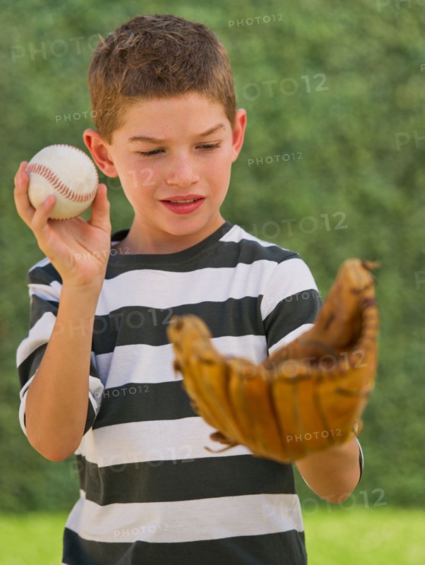 Boy (10-11) holding baseball and baseball glove. Photo : Daniel Grill
