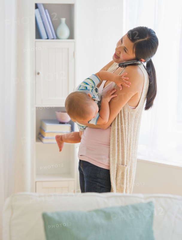 Mother carrying son (6-11 months) and talking on phone. Photo : Daniel Grill