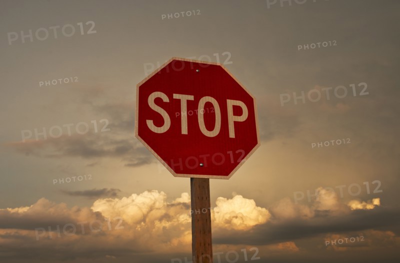 USA, South Dakota, Badlands National Park, Stop sign against sky at sunset.