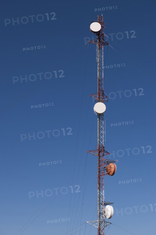 Tele-communications relay tower against blue sky.