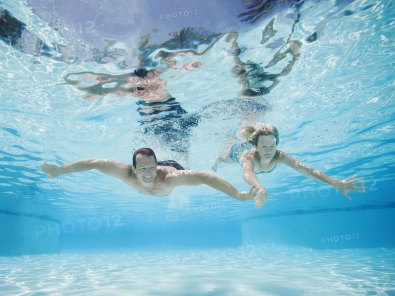 Mid adult couple swimming underwater.