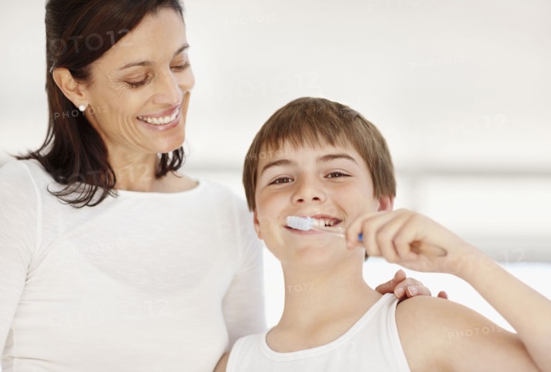 Mother embracing son (12-13)  while he is brushing teeth. Photo : Momentimages