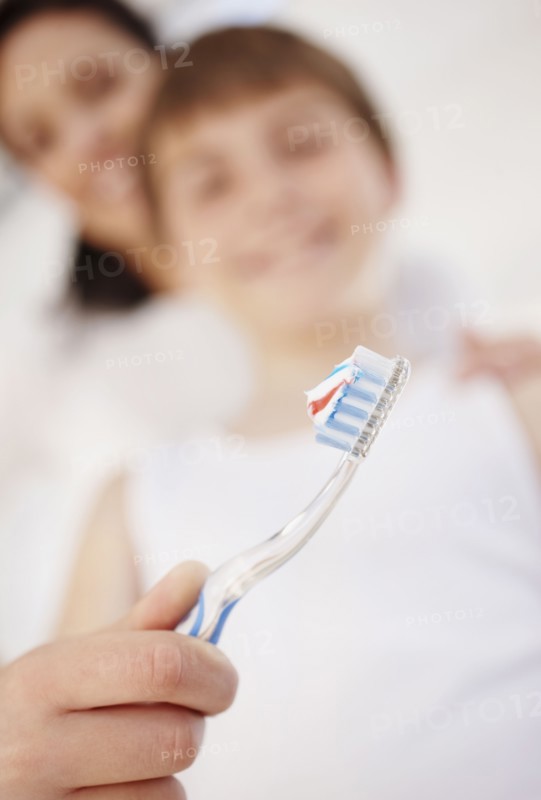 Mother embracing son (12-13) while he is brushing teeth. Photo : Momentimages