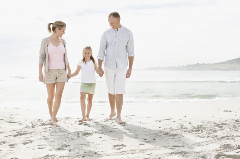 Girl (10-11) playing on beach with parents. Photo : Momentimages