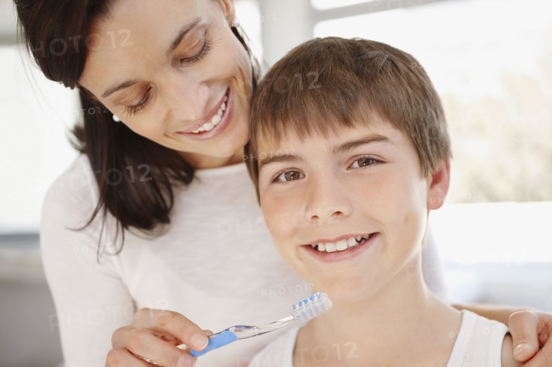 Mother embracing son (12-13) while he is brushing teeth. Photo : Momentimages