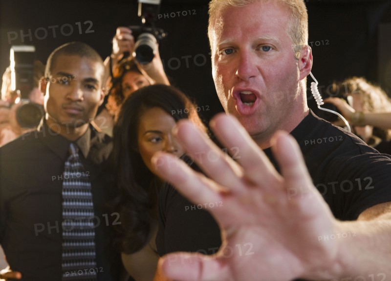 Bouncer shielding celebrity at red carpet event. Photo : Jamie Grill