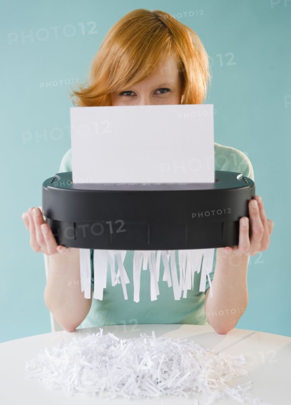 Young woman shredding paper. Photo : Jamie Grill