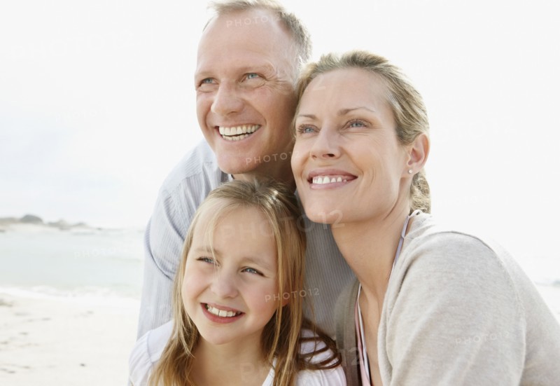 Girl (10-11) playing on beach with parents. Photo : Momentimages