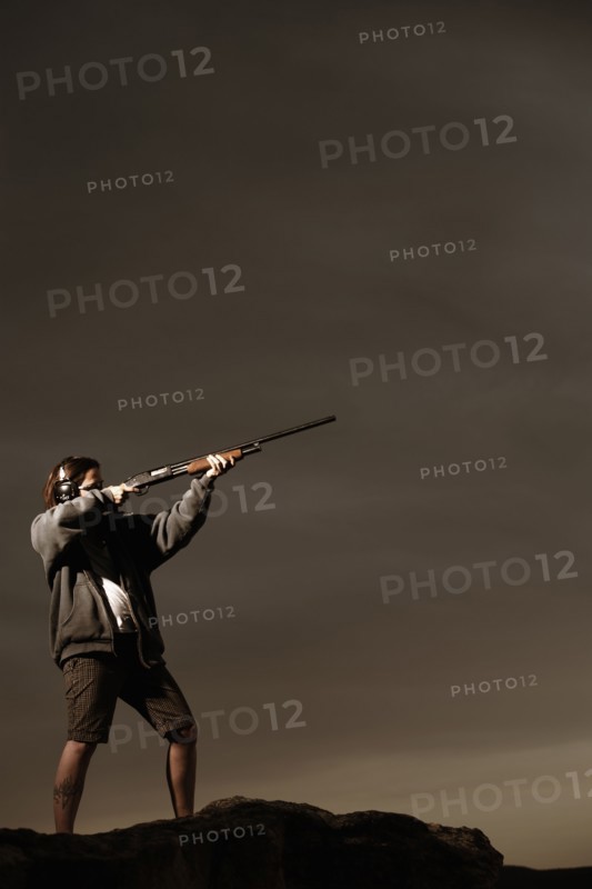 Man aiming rifle on rocks. Photo : Shawn O'Connor