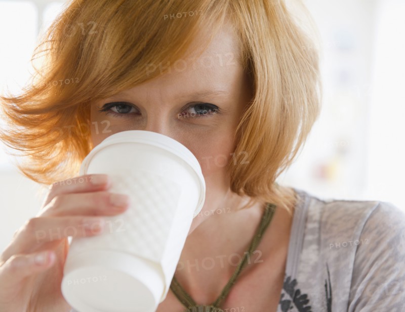 Young woman drinking from disposable cup. Photo : Jamie Grill