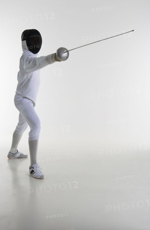 Studio portrait of fencer holding fencing foil.