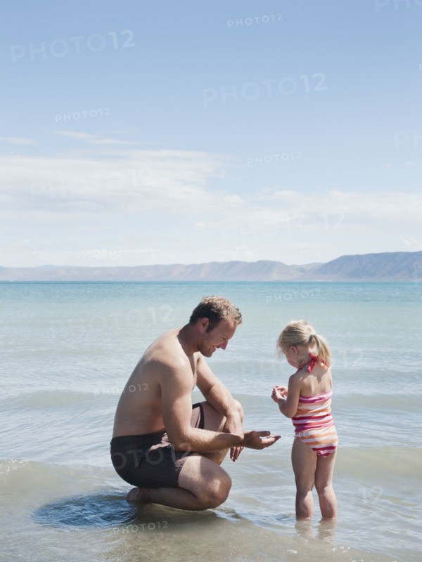 Father and daughter (2-3) at lake.