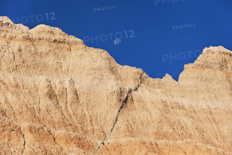USA, South Dakota, Mountain against blue sky with moon in Badlands National Park.