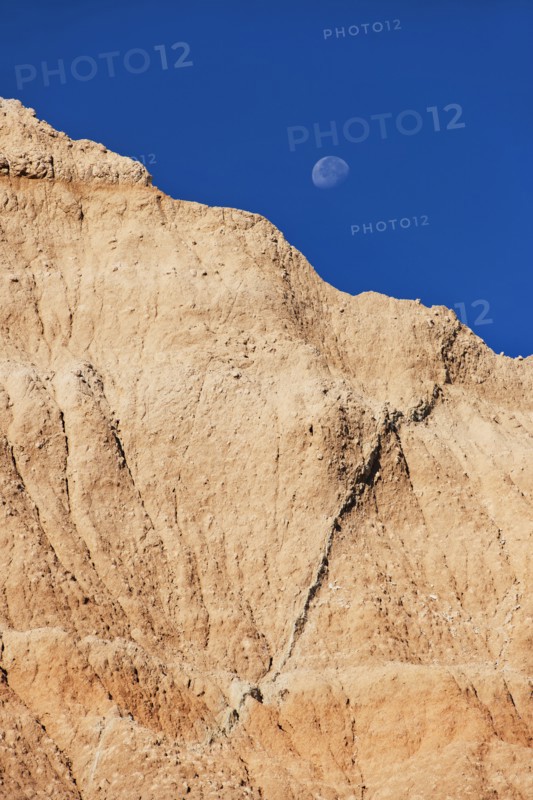 USA, South Dakota, Mountain against blue sky with moon in Badlands National Park.