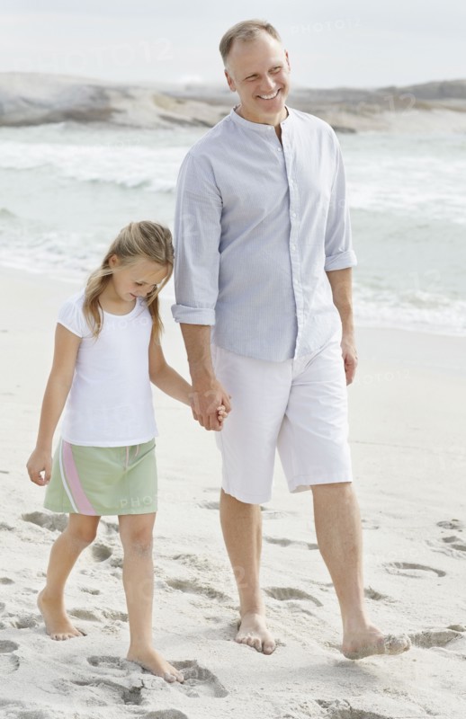 Girl (10-11) playing on beach with father. Photo : Momentimages