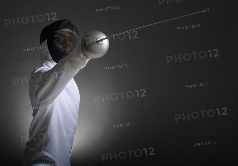 Studio portrait of fencer holding fencing foil.