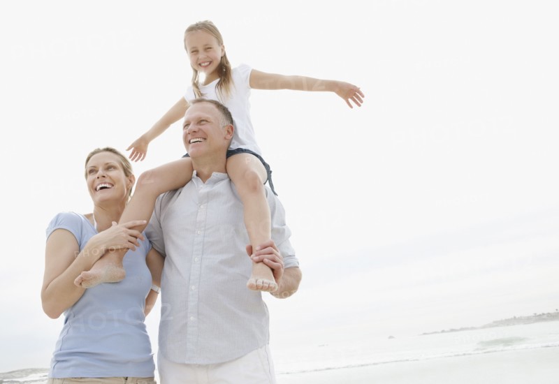 Girl (10-11) playing on beach with parents. Photo : Momentimages