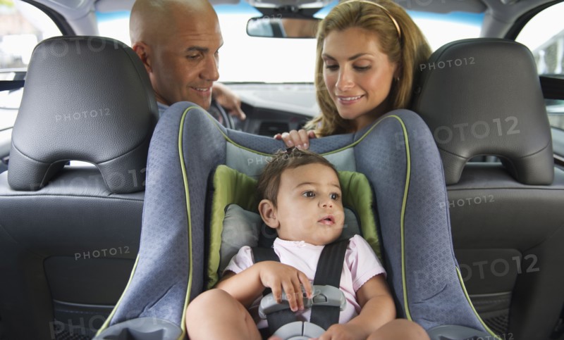 Young family with small girl (12-18 months) sitting in car.