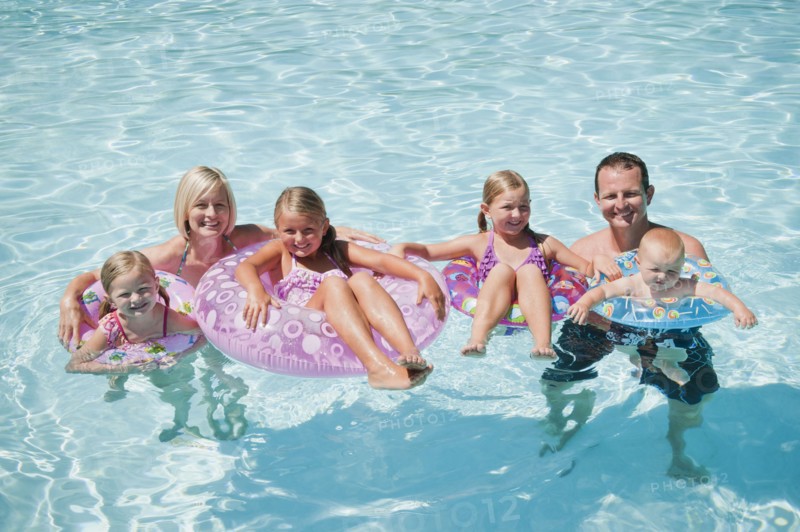 Family with four kids (12-18months, 4-5,6-7,8-9) on swimming pool.